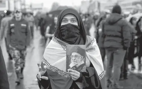  ?? EBRAHIM NOROOZI AP ?? An Iranian woman holds up a portrait of Iranian Supreme Leader Ayatollah Ali Khamenei, as she makes the victory sign during a rally marking the 40th anniversar­y of the 1979 Islamic Revolution, in Tehran, Iran, on Monday. •