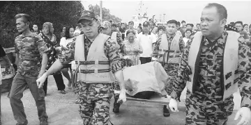  ??  ?? Firefighte­rs carry Steward’s body to the SAR centre at Kampung Muhibbah jetty.