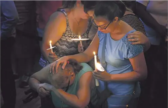  ?? Carolyn Cole Los Angeles Times ?? AT A VIGIL in downtown Orlando, loved ones mourn the victims of the nightclub attack. The shooting left 49 people dead and more than 50 others wounded.