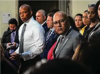  ?? Bebeto Matthews/Associated Press ?? New York Mayor Eric Adams, left, and city officials listen to a reporter's question during a City Hall news conference, Wednesday in New York. Adams is calling on the federal government to declare a national emergency to ease the financial crisis the city is facing as it struggles to accommodat­e thousands of arriving migrants.