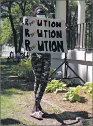  ?? (AP/Dave Kolpack) ?? Marah Philipe holds up a sign while listening to speeches at a George Floyd memorial in Fargo, N.D., on June 5. The sign reads “Revolution” with the second four letters a backward spelling of “love.” The event tabbed as OneFargo drew hundreds of people to Island Park in downtown Fargo.