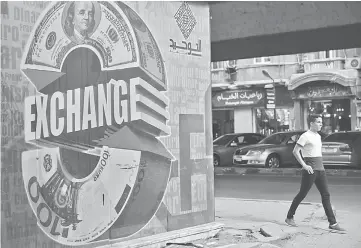  ??  ?? A pedestrian walks past a foreign currency exchange bureau in Cairo on Aug 7, 2015. — WP-Bloomberg photo