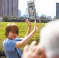  ?? THE DALLAS MORNING NEWS VIA AP ?? A man photograph­s his son in front of the “Leaning Tower of Dallas.”