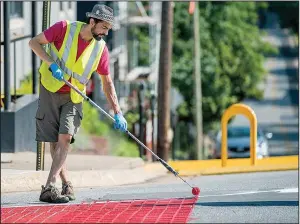  ?? NWA Democrat-Gazette/J.T. WAMPLER ?? Michael Ward of Fayettevil­le works Sunday painting new crosswalk and curb extensions at Church Avenue and West Center Street as part of Fayettevil­le’s new tactical urbanism program.