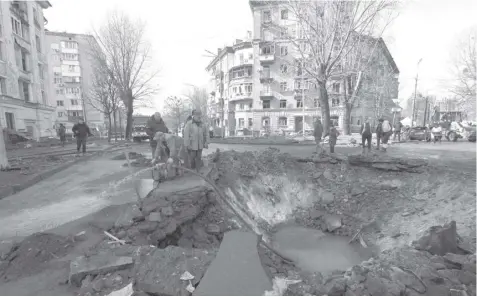  ?? (PHOTO BY SERGEI CHUZAVKOV / AFP) ?? Ukranian municipal services workers survey and repair the damage following a missile attack in Kyiv, on March 21, 2024, amid the Russian invasion of Ukraine.