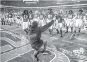  ?? AL DIAZ adiaz@miamiheral­d.com ?? UM coach Manny Diaz slides across a field tarp as he celebrates with players after defeating the Virginia Cavaliers 19-14 at Hard Rock Stadium on Oct. 24.