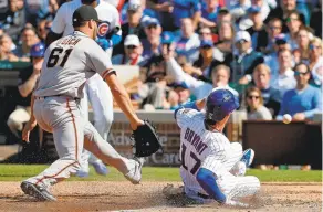  ?? JON DURR/GETTY IMAGES ?? Kris Bryant slides in to score on a wild pitch for the Cubs on Thursday in the eighth inning as Josh Osich is unable to handle the throw from catcher Buster Posey.