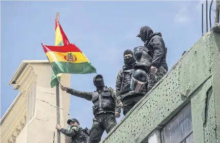  ?? BLOOMBERG ?? Members of the Bolivian Police Special Operations Tactical Unit wave Bolivian flags at their headquarte­rs near the Presidenti­al Palace in La Paz, Bolivia, on Saturday.