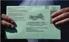  ?? Photograph: Robyn Beck/AFP/Getty Images ?? A voter displays their mail-in ballot envelope as they arrive to cast their ballot in Phoenix, Arizona.