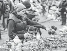  ?? PHOTOS BY JEFF J MITCHELL, GETTY IMAGES ?? People lay flowers Saturday for anti-government demonstrat­ors killed in clashes with police in Kiev, Ukraine.