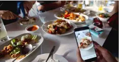  ??  ?? A customer takes photos of food cooked by Thai cook Supinya Jansuta, 72, better known as “Jay Fai,” at her eatery in Bangkok, Thailand.