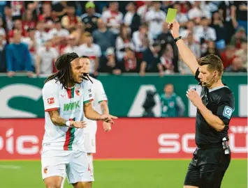  ?? Foto: Peter Fastl, Kolbert-press ?? Kevin Mbabu kann es nicht fassen. Schiedsric­hter Patrick Ittrich zeigt ihm gegen den VFB Stuttgart die Gelbe Karte. Es ist seine fünfte. Darum wird der Fca-spieler beim Saisonfina­le in Leverkusen fehlen.