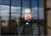  ?? ?? Salvadoran Catholic Father Edgardo Rivera, 42, looks Nov. 28 through the window of the community center where Mass is held in Riego del Camino in the Zamora province of Spain. Their church has been closed for several years due to the roof’s state of ruin.