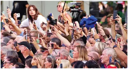  ?? ?? Sea of phones: Mourners hold their mobiles up to film the solemn procession as it passes by