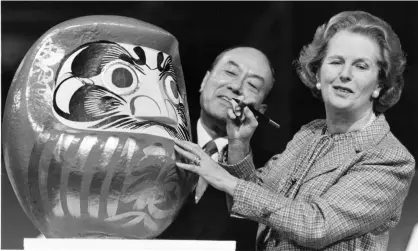  ?? Photograph: Alamy ?? Margaret Thatcher with a Japanese Daruma doll during the opening ceremony for the Nissan factory in Sunderland, 1986.