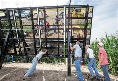  ?? AP/NATI HARNIK ?? Volunteers and installers push a solar panel array into place on farmer Jim Carlson’s cornfield near Silver Creek, Neb., on Saturday. The proposed Keystone XL pipeline route takes it across Carlson’s farm, and the panel is a form of protest.