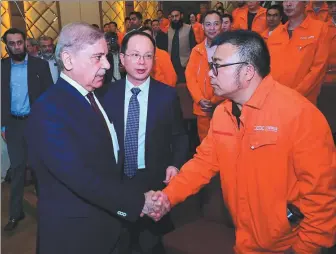  ?? PAKISTAN PRESS INFORMATIO­N DEPARTMENT VIA AGENCE FRANCE-PRESSE ?? Pakistan’s Prime Minister Shehbaz Sharif (left) shakes hands with an engineer from the China Gezhouba Group working at the Dasu Hydropower project in the Upper Kohistan district of Khyber Pakhtunkhw­a Province on Monday.