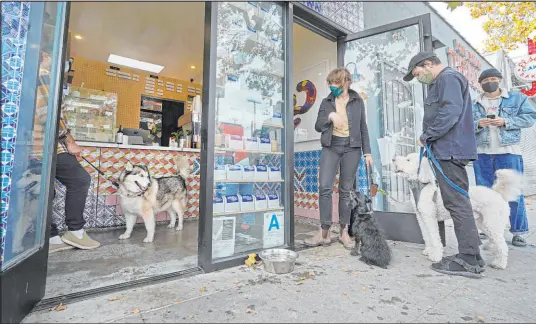  ?? Damian Dovarganes The Associated Press ?? Patrons with their dogs social distance outside Collage Cafe in the Highland Park neighborho­od of Los Angeles on Saturday. A vaccine mandate took effect Monday in Los Angeles requiring proof of shots for everyone entering a wide variety of businesses.