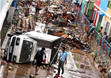  ?? — Reuters photo ?? A vehicle lies on its side among debris along a road after flash floods brought by continuous monsoon rains in Marikina, Metro Manila.