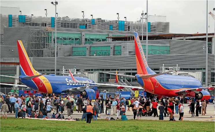  ??  ?? Passengers and staff who fled the terminal at the Fort Lauderdale airport as a gunman killed five people wait on the tarmac for police to give the all-clear.