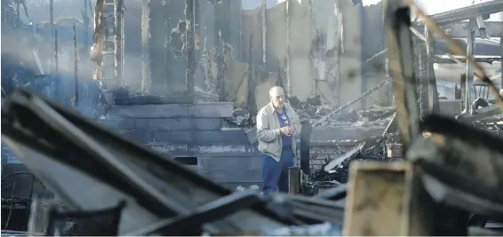  ??  ?? Dick Marsala looks for his wallet Friday in the smoulderin­g remains of his home in the Rancho Monserate Country Club north of San Diego.