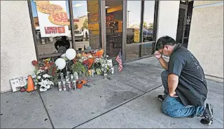  ?? ETHAN MILLER/GETTY PHOTO ?? Jonathan Solano prays Monday at a memorial outside CiCi’s Pizza in Las Vegas where two officers were killed.