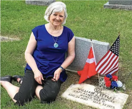  ?? PHOTO PROVIDED ?? Linda Berkery sits at the grave of her father, William Styles, a World War II bomber pilot whose dramatic rescue from the North Sea in 1943 was unknown to Berkery and her sisters until recently.