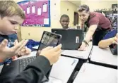  ?? JACOB LANGSTON/ STAFF PHOTO ?? Altamonte Elementary 4th-grade teacher Michael Circe checks Taborri Defranca’s work during a coding lesson.