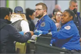  ?? AP/MICHAEL DWYER ?? Transporta­tion Security Administra­tion officers Logan Internatio­nal Airport in Boston. move travelers through a checkpoint Saturday at