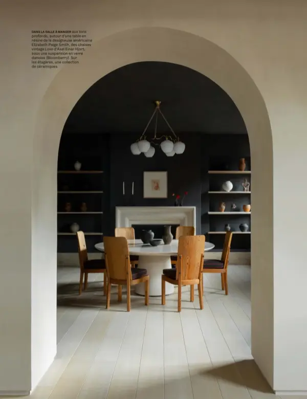  ??  ?? DANS LA SALLE À MANGER aux tons profonds, autour d’une table en résine de la designeuse américaine Elizabeth Paige Smith, des chaises vintage Lovo d’Axel Einar Hjort, sous une suspension en verre danoise (Bloomberry). Sur les étagères, une collection de céramiques.