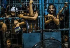  ??  ?? Inmates at a Manila police station watch as drug suspects are processed after their arrests.