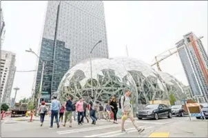  ?? STUART ISSET/THE NEW YORK TIMES ?? Pedestrian­s walk past a recently built trio of geodesic domes that are part of the Seattle headquarte­rs for Amazon on Thursday.