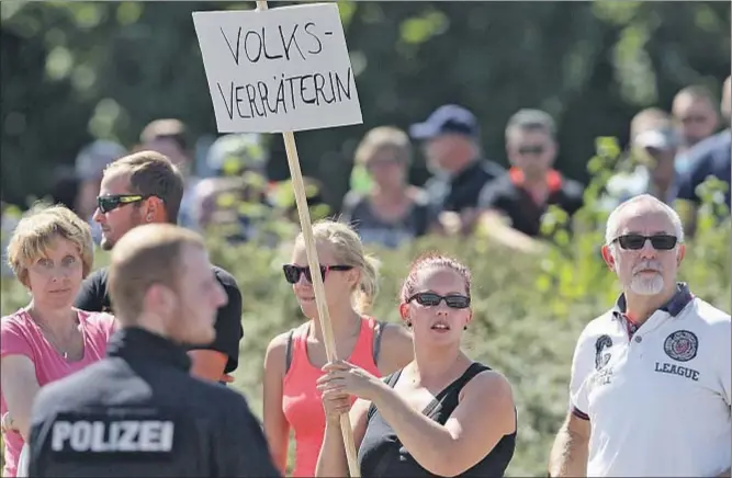  ?? SEAN GALLUP / GETTY ?? Una manifestan­te enarboland­o un cartel en el que acusa a Merkel de “traidora a la nación”, ayer en la localidad de Heidenau