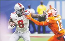  ?? KEVIN C. COX/ GETTY IMAGES ?? Trey Sermon of the Ohio State Buckeyes holds off Joseph Charleston of the Clemson Tigers in the College Football Playoff semifinal game on New Year's Day. Ohio won, advancing to the final.
