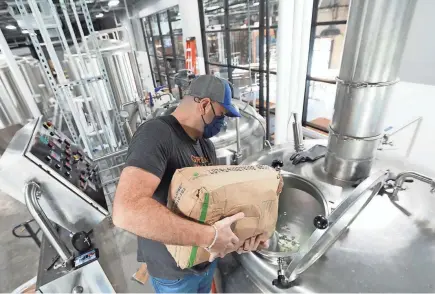  ?? DORAL CHENOWETH, DORAL CHENOWETH/DISPATCH ?? Brewmaster Zack Null adds sugar to a boil kettle as he makes seltzer at Crooked Can Brewery in Hilliard. More craft breweries have opened than closed during the pandemic.