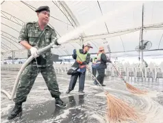  ?? CHANAT KATANYU ?? A military officer and City Hall workers clean an area in Sanam Luang for a cleaning day event that will pay tribute to the late King.