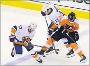  ?? FRANK GUNN — THE CANADIAN PRESS VIA AP ?? Philadelph­ia Flyers center Sean Couturier (14) tries to hold onto the puck under pressure from New York Islanders center Casey Cizikas (53) and teammate Matt Martin (17) during the second period Tuesday.