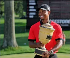  ??  ?? In this 2013, file photo, Tiger Woods holds the trophy after winning the Bridgeston­e Invitation­al golf tournament at Firestone Country Club in Akron, Ohio.
AP PhoTo/PhIl long
