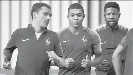  ?? Franck Fife AFP/Getty Images ?? FRENCH PLAYERS, from left, Antoine Griezmann, Kylian Mbappe and Samuel Umtiti practice in Moscow for the championsh­ip game.