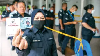  ?? Sanusi — Photo by Muhammad Rais ?? A police personnel shows her Mykad and also a slip indicating her queue number.