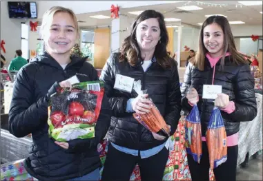  ?? ANDREA PEACOCK/The Daily Courier ?? Central Okanagan Community Food Bank volunteers Sadie Tubello, left, Kendra Dunn, centre, and Sophia Dunn hand out food to people at the food bank in Kelowna Monday morning.