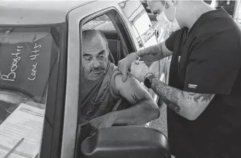  ?? Jerry Lara / Staff file photo ?? Raul Garza, 55, gets his COVID-19 booster shot in September at a drive-thru clinic at the Alamodome set up by the Metropolit­an Health District. In December, at least 1.2 million Texans have gotten booster shots.