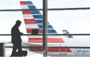  ?? PHOTO BY SUSAN WALSH/AP FILE ?? A passenger talks on the phone as an American Airlines jet sits parked at their gates at Washington’s Ronald Reagan National Airport. Ten people were injured last weekend as an American Airlines flight plowed through turbulence on its way to landing in...