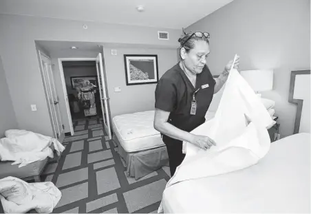  ??  ?? Room attendant Ana Venegas puts on new bedsheets in an Embassy Suites room. OTC typically flushes hotels with customers.