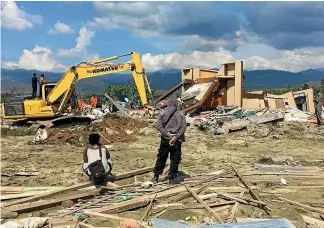  ?? WASHINGTON POST ?? Heavy machinery digs through the ruins of a church to find bodies likely to be buried underneath in Jono Oge, Indonesia.