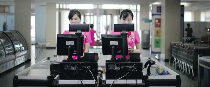  ?? PHOTOS: WONG MAYE- E / THE ASSOCIATED PRESS ?? Cashiers stand at checkout counters wait to serve customers at the Potonggang department store in the North Korean capital Pyongyang.