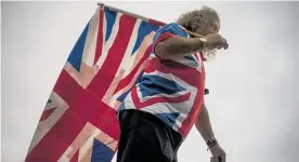  ?? Photos / AP ?? A man carries a Union Jack flag marking the death of Prince Philip.