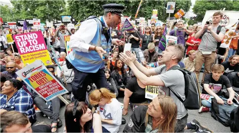  ?? — Reuters photo ?? A police officer tells demonstrat­ors to move during a sit-down protest outside Downing Street at an anti-austerity rally and march organised by campaigner­s Peoples’ Assembly, in central London.