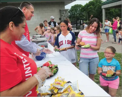 ?? Photos by Ernest A. Brown ?? Tailyn Ilacqua, 6, and Ashley Farquhar of Woonsocket, right, collect some lunch during the kickoff of the City of Woonsocket Summer Lunch Program Thursday at World War II Veterans Memorial Park. School Superinten­dent Patrick McGee, second from left,...