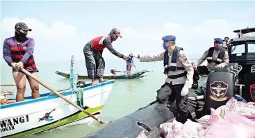  ?? AZAMI RAMADHAN/JAWA POS ?? DEMI KEAMANAN: Wadir Polairud Polda Jatim AKBP Riswanto membagikan masker kepada nelayan yang tengah melaut kemarin.